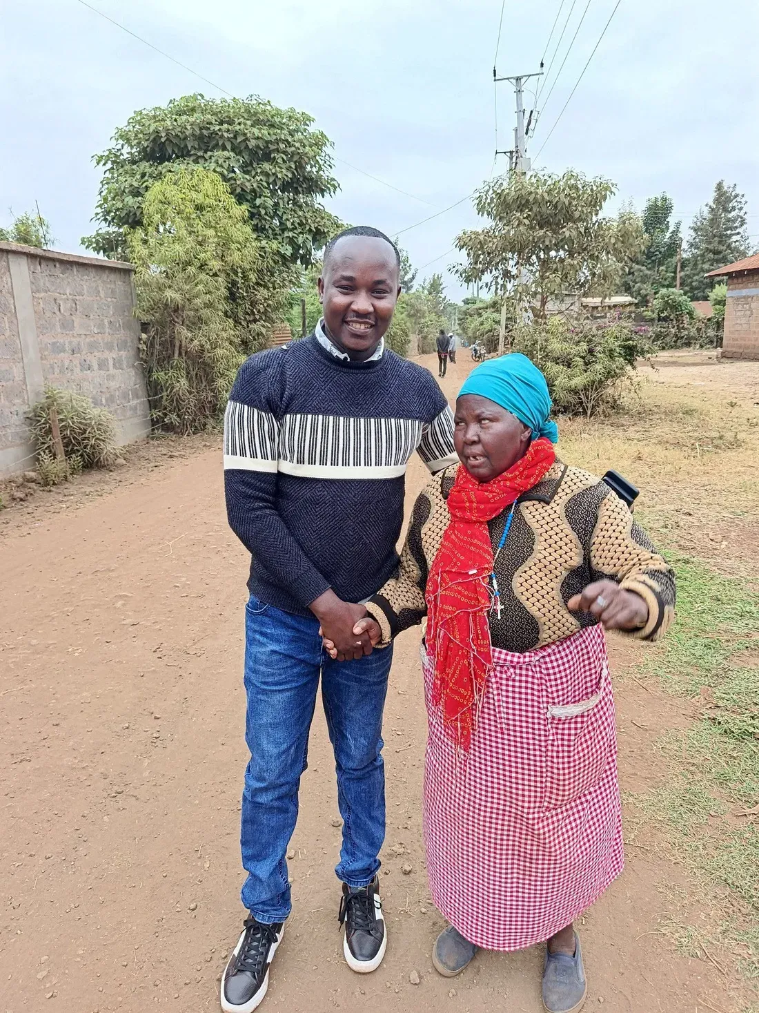 Bernard Karanja with an elderly woman from the community on a village road